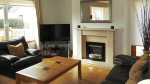 A living room with a flat-screen TV, fireplace, leather sofas, and a coffee table.