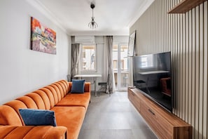 A modern living room with a sofa, TV, and artwork on the wall.