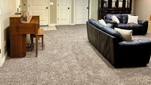 A living room with a piano, a black leather sofa, and a cabinet. - KING bed, 2-bedroom, full kitchen, pickleball, park. Private, spacious basement. (Hooper)
