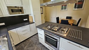 Una cocina moderna con armarios blancos, estufa a gas, horno y encimera negra.
