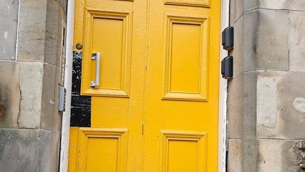 Puerta amarilla con el número 133, ubicada en un edificio de piedra.
