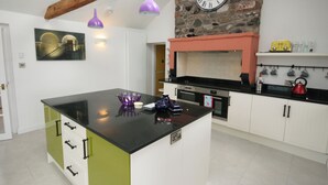 A modern kitchen with a central island, built-in oven, and pendant lighting.