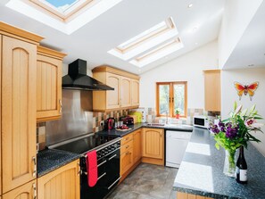 Eine moderne Küche mit Oberlichtern, Holzschränken, Edelstahlgeräten und einer dekorativen Wandkunst mit Schmetterlingen.