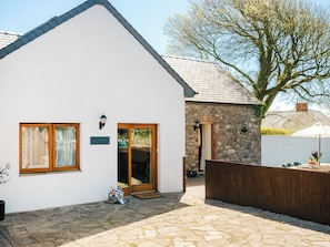 A white building with a stone wall, a wooden door, and a stone-paved courtyard.