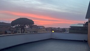 Kattoterassi, jossa on laatoitettu lattia ja josta avautuu näkymä auringonlaskuun.