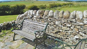 A stone wall with a bench in a rural setting.