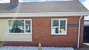 A brick building with two windows, a nameplate reading 'The Five Fishers,' and a statue in the foreground. - The Five Fishers Beadnell (Beadnell)