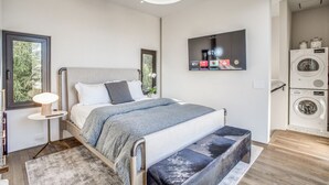 Une chambre à coucher moderne avec un lit, une table de chevet et un téléviseur fixé au mur.