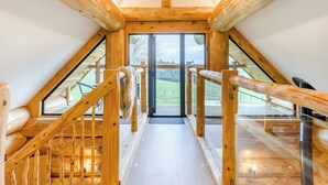 Un escalier en bois mène à une porte vitrée, d’où l’on peut admirer un espace verdoyant à l’extérieur.