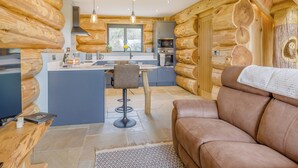 L’intérieur d’une cabane en rondins comprend une cuisine, un coin repas et un canapé.