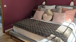 Une chambre à coucher avec un lit, des oreillers, un lustre et une table de chevet.