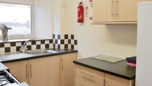 A compact kitchen with a window, a sink, and a stove.