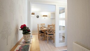 Un coin repas avec une table et des chaises en bois, une plante en pot et une horloge au mur.