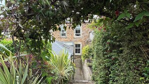 A narrow stone pathway leading to a stone building with multiple windows and a sloped roof. - Stylish Elie Beach Retreat sea-view and Sunny deck (Elie and Earlsferry)