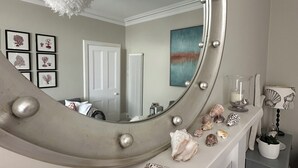 A mirror with decorative lights, a white fluffy light fixture, and various seashells on a shelf. - Stylish Elie Beach Retreat sea-view and Sunny deck (Elie and Earlsferry)