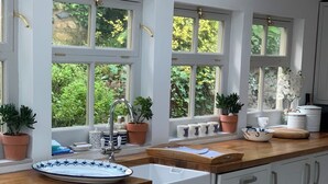 Une cuisine avec des meubles blancs, un plan de travail en bois et une fenêtre donnant sur un paysage verdoyant.