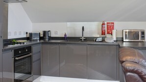 A modern kitchen with a built-in oven, a microwave, a coffee maker, and a sink. - 1 bedroom accommodation in Dippen, near Whiting Bay, Isle of Arran (Dippen, near Whiting Bay, Isle of Arran)