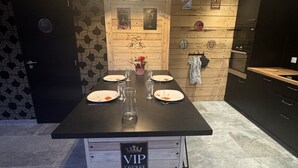 Ein moderner Essbereich mit einem schwarzen Tisch, gedeckt für vier Personen, einer Holzvertäfelung und einem Schild für eine VIP-Lounge.