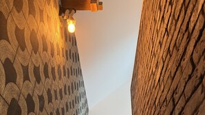 Eine Treppe mit einer Wand mit Muster auf einer Seite und einer Backsteinwand auf der anderen, die zu einer höheren Etage führt.