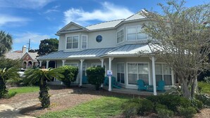 A two-story house with a covered porch and a large tree in the front yard. - Blast at the Beach - Golf Cart Available to Rent! Pet Friendly! (Destin)