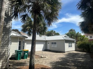 Um imóvel residencial com garagem, calçada pavimentada e uma palmeira.