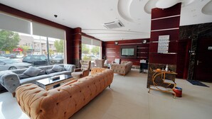 Un vestíbulo de hotel con zona de estar, mostrador de recepción y una pantalla de televisión.