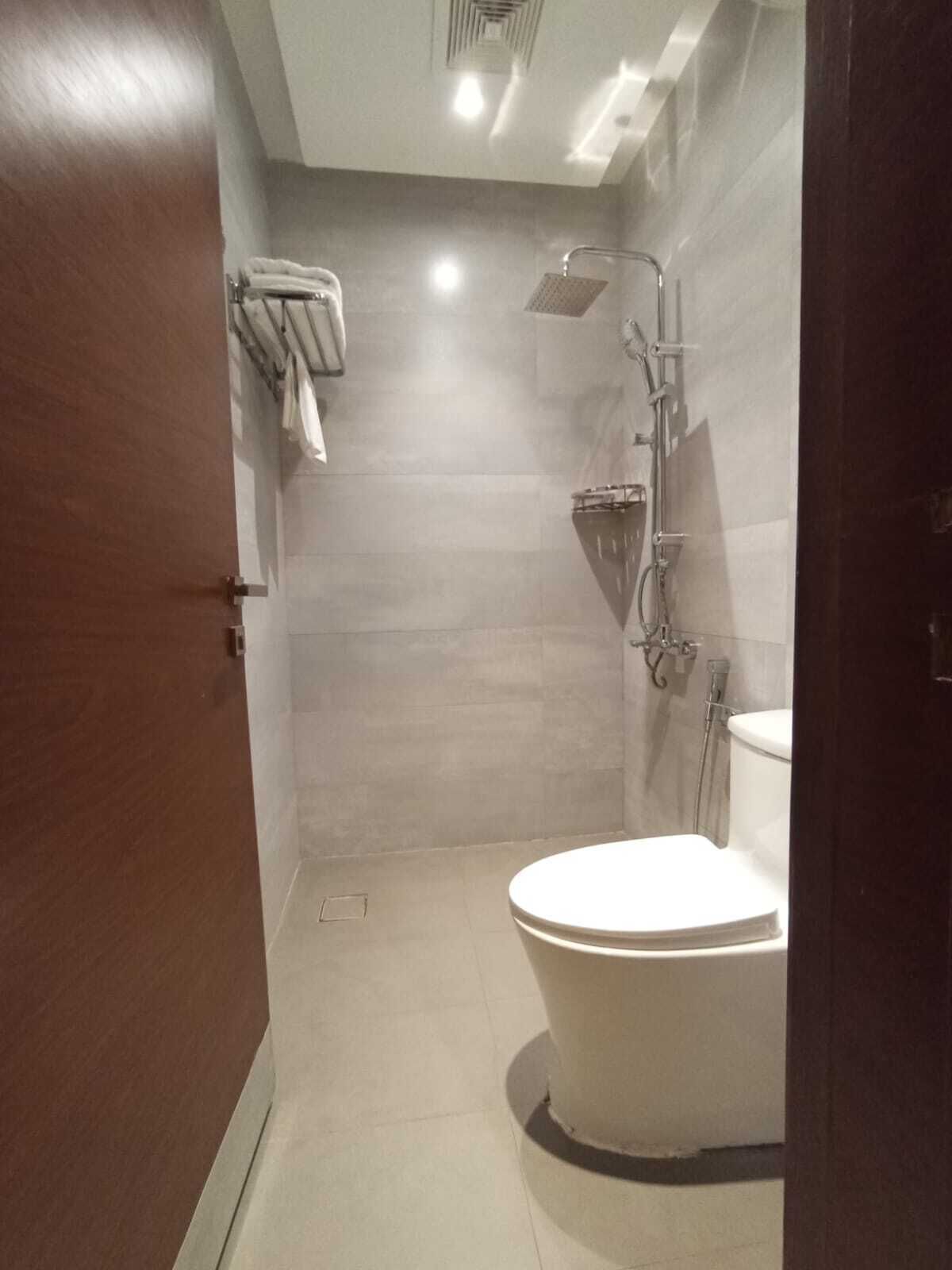 A modern bathroom with a toilet, a shower, and a towel rack.