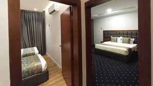 Una habitación de hotel con una cama, un pequeño rincón de descanso y un ventanal con cortinas.