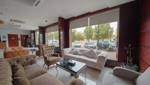 Un vestíbulo amplio con una zona de estar grande, un mostrador de recepción y ventanas grandes que ofrecen vista a la calle.