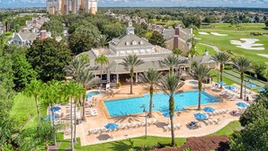 A resort with a large swimming pool, palm trees, and a golf course in the background. - Fairview at Reunion - Games Room (Kissimmee)