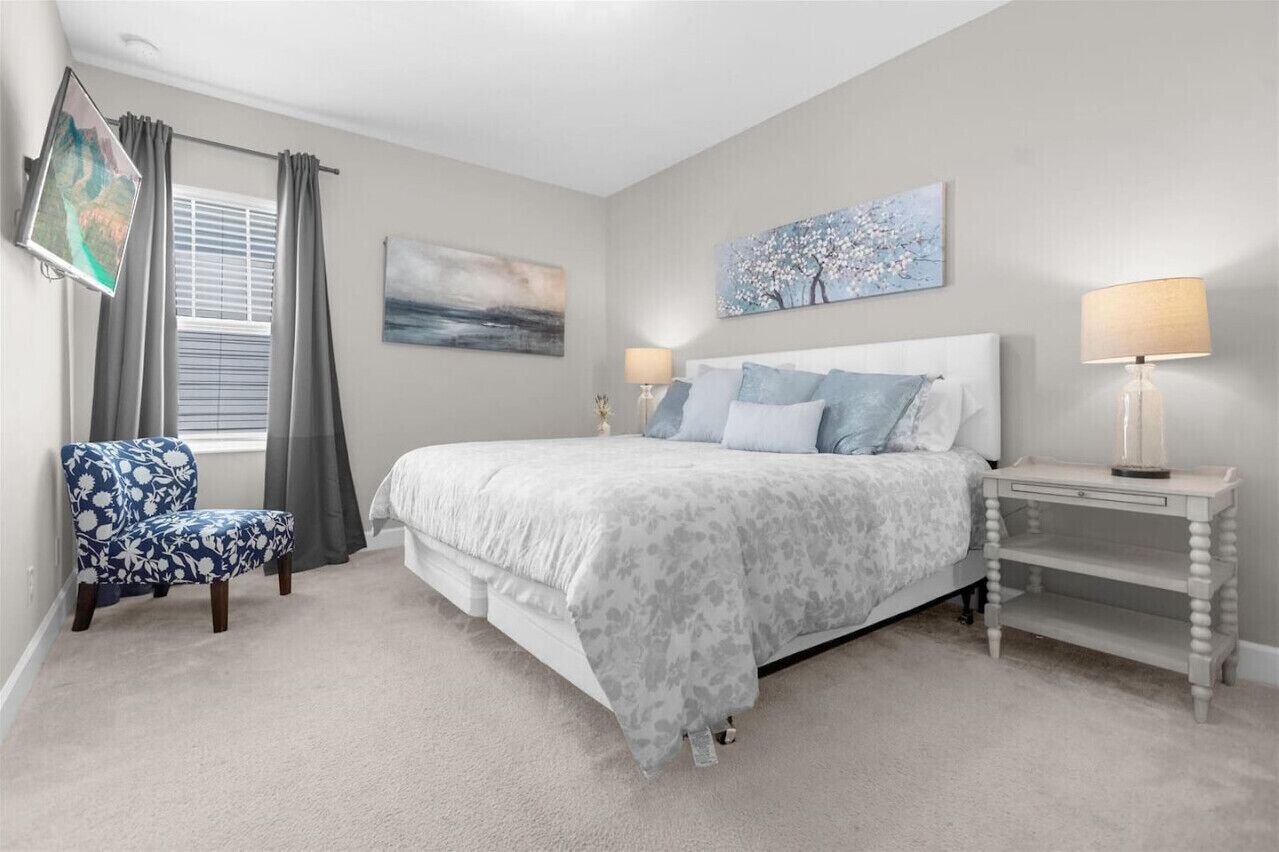 A bedroom with a bed, two bedside tables, a chair, and a window with curtains.