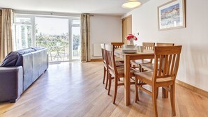 Un coin repas avec une table en bois, des chaises et un vase de fleurs.