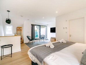 A modern hotel room with a bed, a desk, a chair, and a TV.