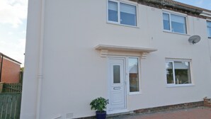A two-story residential building with a white exterior, a front door, and a satellite dish. - Situated close to all the amenities of the fishing port of Whitby. (Whitby)
