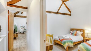 Camera da letto con due letti, travi in legno, una sedia e una scrivania.