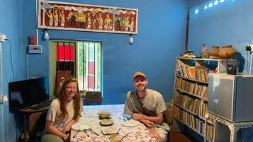 A room with a blue wall, a bookshelf, a table with food, and a television.