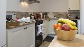 A modern kitchen with white cabinets, a stainless steel oven, a microwave, and a wooden countertop. - 3 bedroom accommodation in Rhyd Ddu, Caernarfon (Rhyd Ddu, Caernarfon)