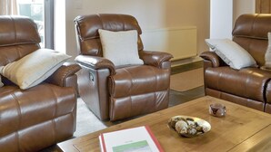A room with two brown leather recliners, a wooden coffee table with a book and a bowl of fruit, and a radiator. - 3 bedroom accommodation in Rhyd Ddu, Caernarfon (Rhyd Ddu, Caernarfon)