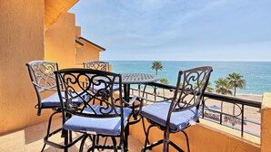 Un balcone con tavolo e sedie, vista su una spiaggia con palme e il mare.