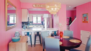 A kitchen with a central island, a dining area with chairs and a table, and a bright pink color scheme. - Pink Dream House in PCB - Beach, Pools, Hot Tub, Clubhouse, Dog-Friendly (Panama City)