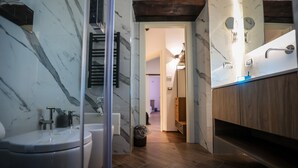 Un baño moderno con salpicadero de mármol, suelo de madera y cabina de ducha de vidrio.