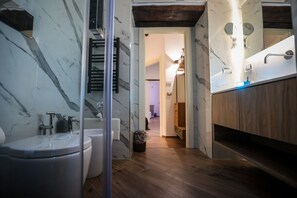 A modern bathroom with a marble backsplash, a wooden floor, and a glass shower enclosure. - Petramare Charming House  (Salerno)