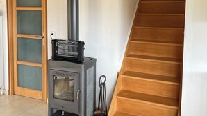 A wood-burning stove in a room with a wooden staircase and a door with frosted glass panels. - Small house on a hill, quiet with sea view, sunny terrace (Menton)
