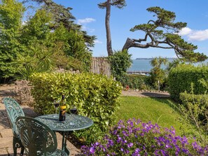 A garden with a table, chairs, and a view of the sea.