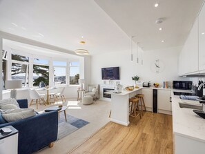 Una cucina moderna con una TV, sgabelli da bar in legno e vista sulla città.