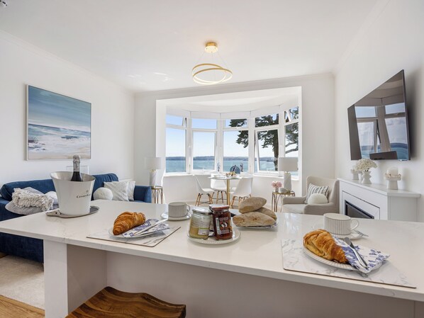 A modern kitchen with a dining area, a large window with a view, and a white interior.