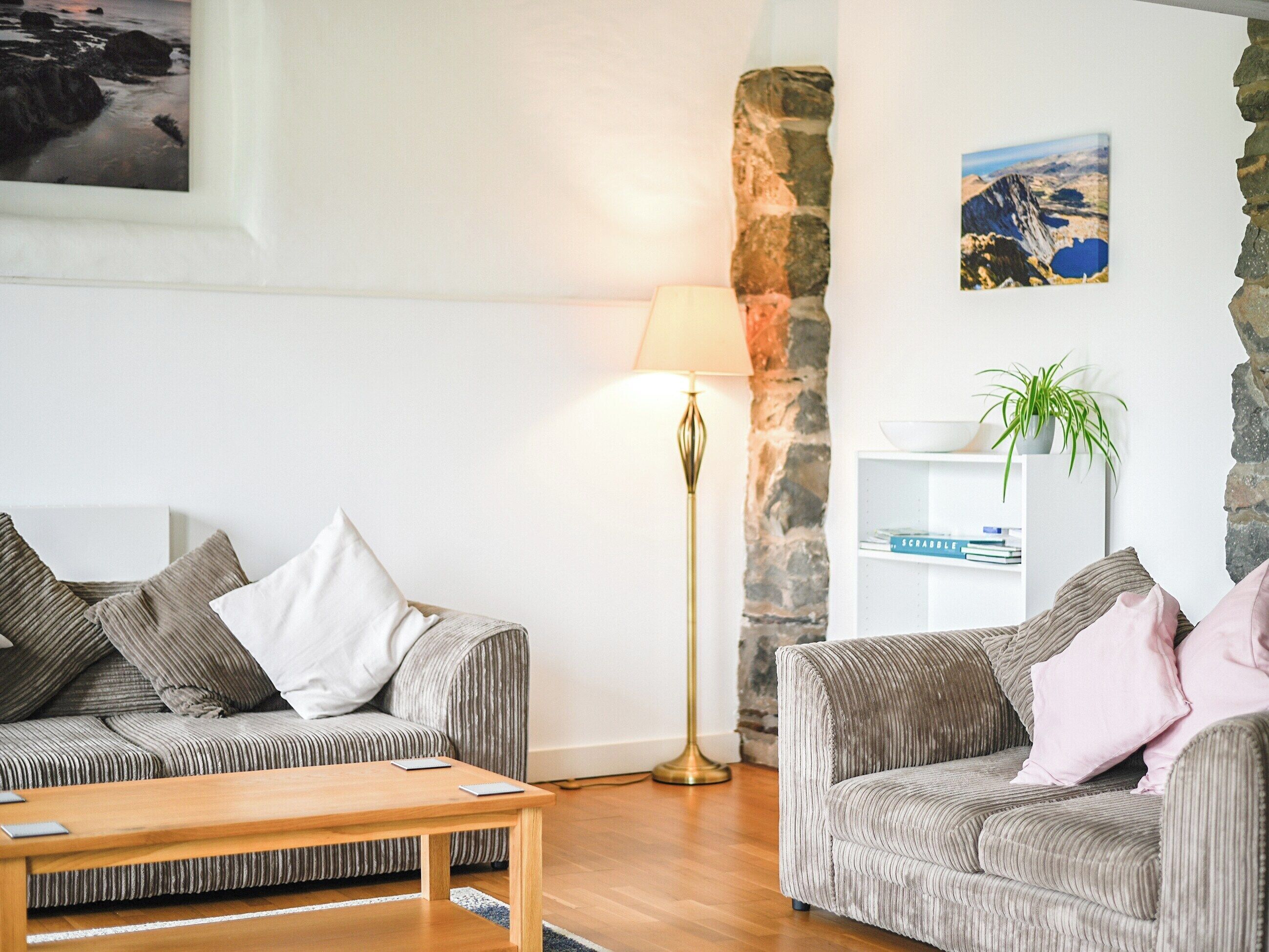 A living room with two sofas, a coffee table, a lamp, a bookshelf, and a painting on the wall.
