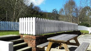 A picnic table and steps leading to a white picket fence. - 2 bedroom accommodation in Corrie, Isle of Arran (Corrie, Isle of Arran)