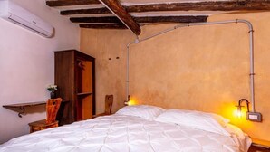 A bedroom with a bed, wooden furniture, an air conditioning unit, and a wall-mounted lamp. - Historic house surrounded by greenery, near outdoor activities and sea (Liguria)
