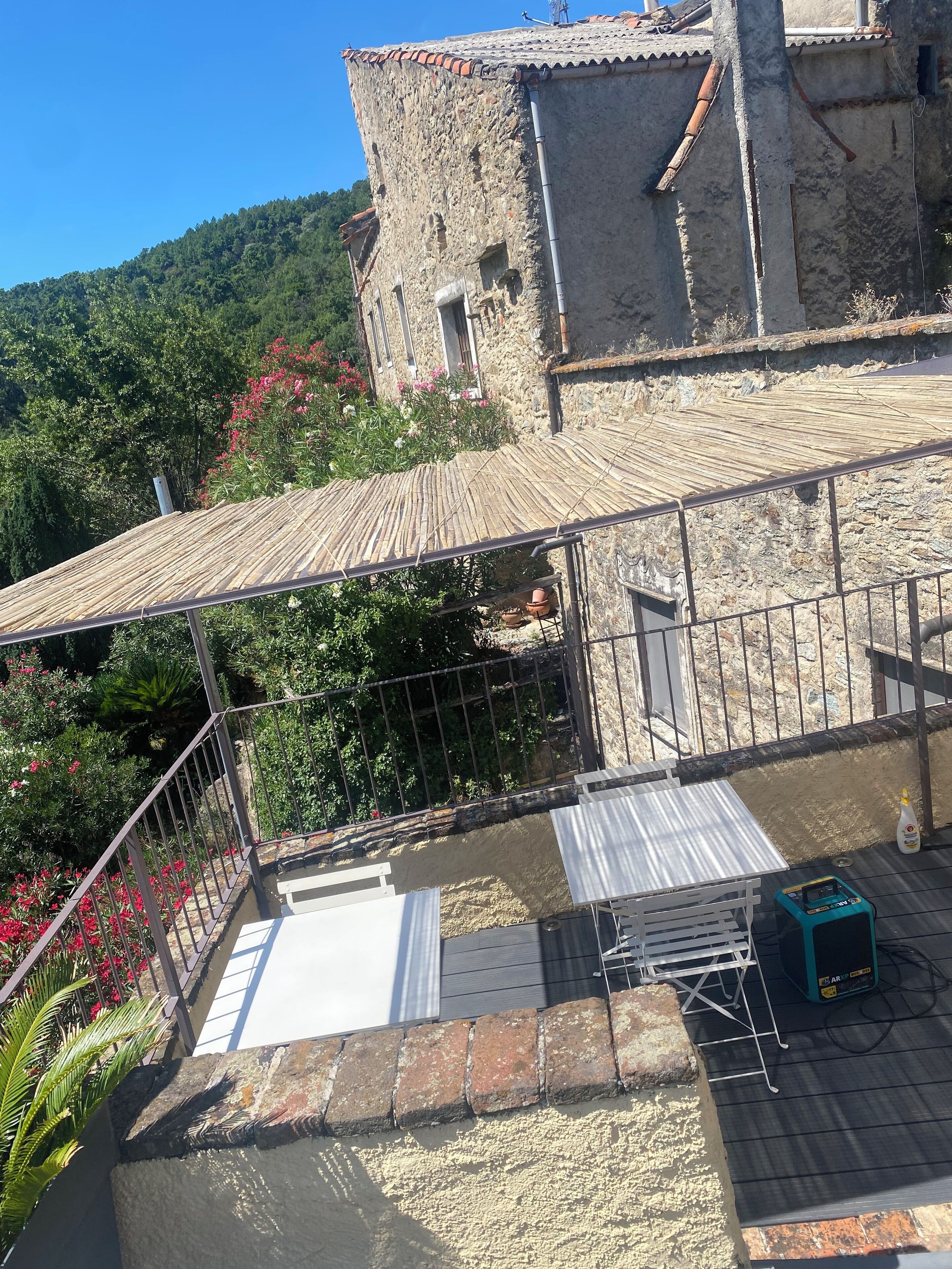 A rooftop terrace with a metal roof, a brick wall, and a view of a forested hillside.